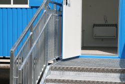 Detailed view of the extra wide 5-step galvanized stairway suitable for children with step-through protection, second handrail, and platform in front of the side entryway.
