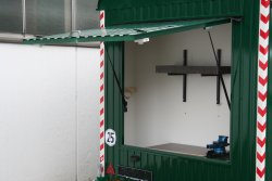 <br>Overhead workshop door with workbench, rotary vise, shelf, and holders for brush cutters.