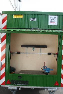 <br>Overhead workshop door with rotary vise, shelf, workbench, and holders for brush cutters.