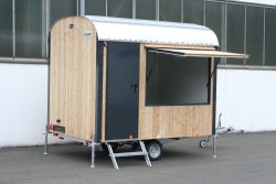 <h5>WEIRO® sales trailer</h5> with 3 m body length, wood outer paneling, painted sheet steel, overhead door on rear, and entryway on the side.