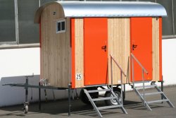 WEIRO® SOLID mit 4 m Aufbaulänge, Zugöse, Stützrad, Dachüberstand, 2 Türen mit Treppe und Handlauf als WC-Wagen. Türen, Eckprofile und Fensterläden in individueller Lackierung.