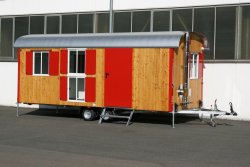 WEIRO® RASANT mit 6 m Aufbaulänge, verzinktes Fahrgestell, Kugelkupplung, Dachüberstand, KSt.-Schiebefenster, teilweise übereinander angeordnet, Kaminofen mit Edelstahl-Schornstein. Individuelle Lackierung von Eckprofilen, Tür und Fensterläden.