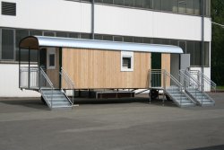 WEIRO® SOLID mit 9 m Aufbaulänge, Zugöse, Dachüberstand, Eingang mit überdachtem Podest, Treppen mit Geländer, Kst.-Drehkippfenster mit Rollladen.