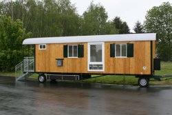 WEIRO® SOLID mit 9 m Aufbaulänge, Zugöse, Dachüberstand, Eingang mit überdachtem Podest, Treppe mit Geländern, bodentiefes Kst.-Drehkippfenster, KSt.-Schiebefenster, Gasheizung, Gerätekasten.