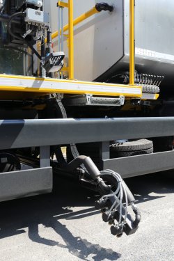 <br>Hydraulisch positionierter Düsenkopf mit drei einzeln ansteuerbaren Düsen für die Naht- und Randversiegelung mit Heißbitumen oder anderen geeigneten Werkstoffen, seitlich zwischen Vorder- und Hinterachse des Trägerfahrzeugs montiert.