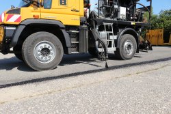 <br>Hydraulisch positionierter Düsenkopf, Version für UNIMOG, mit drei einzeln ansteuerbaren Düsen für die Naht- und Randversiegelung mit Heißbitumen oder anderen geeigneten Werkstoffen, fahrerseitig hinter der Kabine montiert .