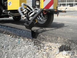 <br>Der Düsenkopf für die Nahtversiegelung sorgt für das gleichmäßige und saubere Auftragen des Bitumens an die Nahtkante (im Bild: Versigeln der Außenkante der Asphaltdecke). <br><p1>Die hier abgebildete Maschine enthält Sonderausstattungen.