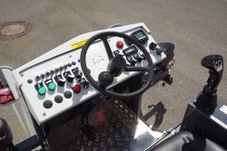 <br>Ergonomisch gestalteter Fahrerplatz, Fahrsteuerung über den Fahrhebel mit Funktionstasten. Option: Rechnergestützte Dosiersteuerung SPRAYCONTROL V4 mit LCD-Steuereinheit rechts vom Fahrerplatz zur genauen Regelung des Bindemittelauftrags (kg/m²), unabhängig von Fahrgeschwindigkeit und Arbeitsbreite. <br><p1>Die hier abgebildete Maschine enthält Sonderausstattungen.
