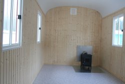 Einrichtungsbeispiel mit Profilholz-Wandverkleidung und Kaminofen