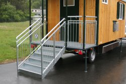 Überdachter Eingang mit Podest, 5-stufige Treppe mit 2 seitlichen Geländern und zusätzlichen Handläufen für Kinder.