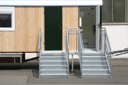 Large platform with two 5-stair stairways, each with 2 railings as direct access to the emergency exit and to the toilet compartment.