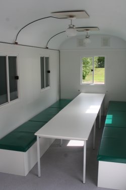 Furnishing example with padded seats suitable for children that cover trunks, with tables, propane ceiling lamps.