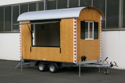 <h5>WEIRO® sales cart</h5> with 3.5 m body length, galvanized tandem chassis, wooden exterior cladding, side wall flap and rear entrance.